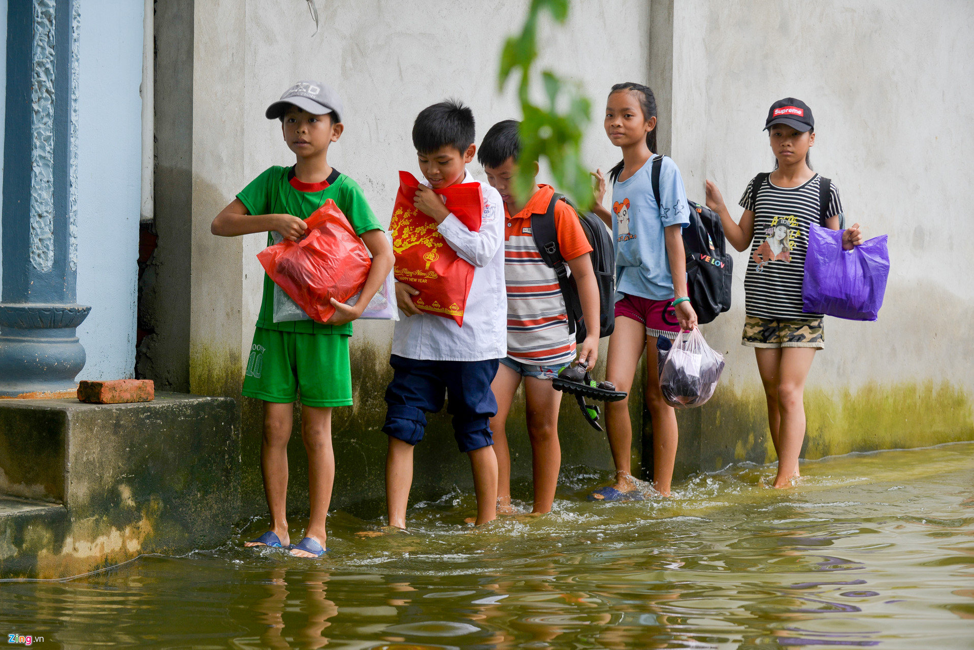 Nhiều em nhỏ phải trèo lên mái nhà hoặc lội nước để tới trường sau 2 tháng nghỉ hè.
