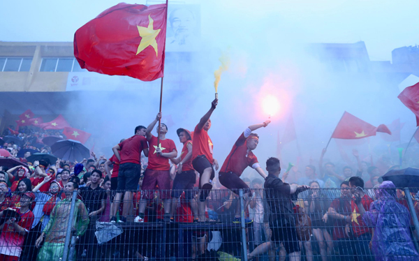 Cổ động viên ở sân Hàng Đẫy (Hà Nội) đốt pháo sáng, phất cờ cổ vũ bất chấp trời mưa nặng hạt và đội nhà bị dẫn trước 3 bàn.