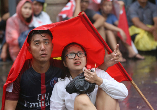Một số fan trú mưa ở các sảnh khách sạn trên đường Nguyễn Huệ (TP HCM) nhưng vẫn hướng mắt về phía các màn hình để ngóng tình hình trận đấu.