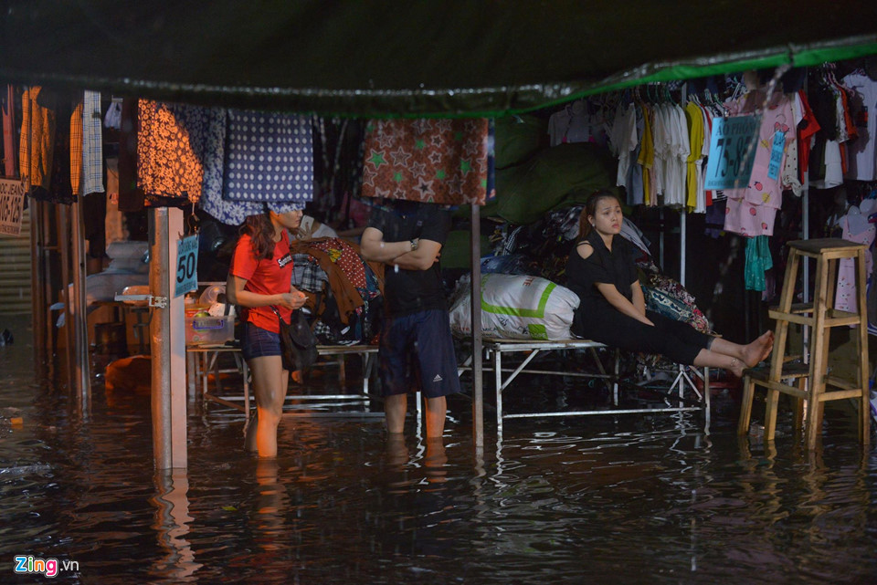 Tiểu thương tại chợ Xanh ở Cầu Giấy chỉ kịp thu dọn đồ chất lên cao và ngồi đợi tạnh mưa, nước rút.