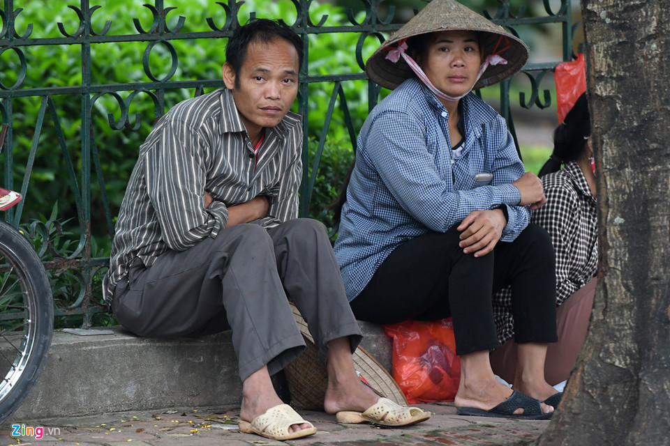 Những người lao động tự do ở đầu cầu Long Biên phía quận Long Biên co ro ngồi bên mép vườn hoa.