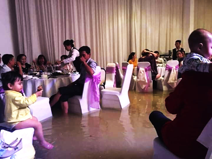Nước từ ngoài đường tràn vào một trung tâm tiệc cưới khiến khách đến ăn cưới phải xắn quần ngồi chúc phúc gia chủ. (Ảnh FB: Hạt lép)