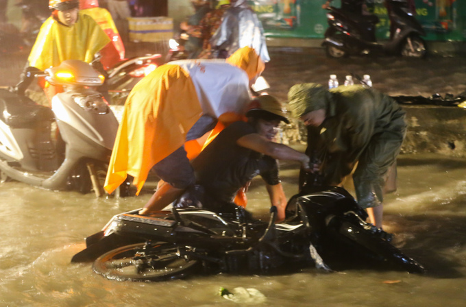 Nhiều người chạy xe máy vấp vào ổ gà trên đường Huỳnh Tấn Phát (quận 7), ngã nhào trong nước.