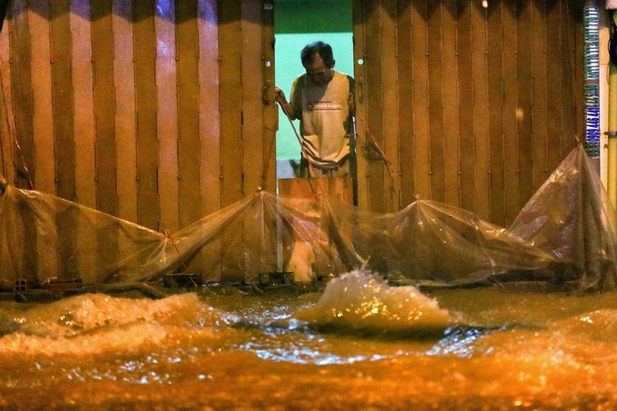 Đến giữa đêm, mưa vẫn trút xuống ở TP HCM. Nhiều nhà dân trên đường Calmette dùng bạt, ván... chắn trước nhà để ngăn nước không tràn vào.