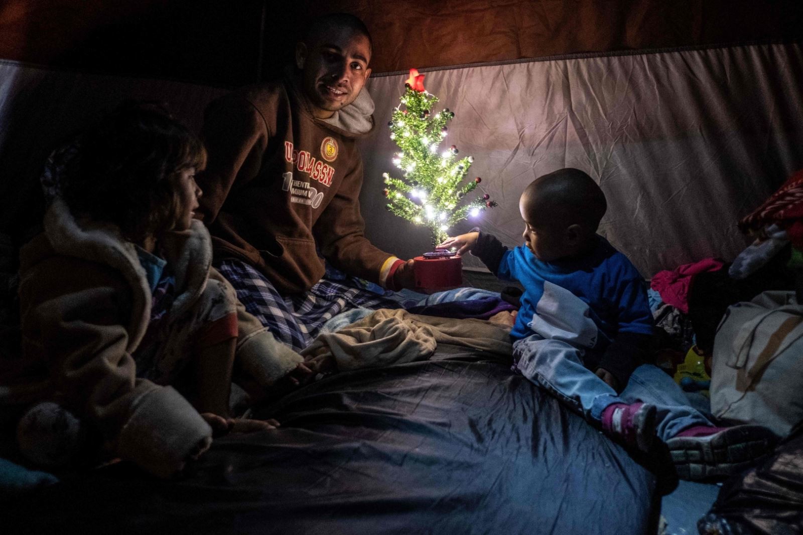 Một gia đình di cư Honduras quây quần bên cây thông nhỏ tại Tijuana, Mexico. (Ảnh: AFP)