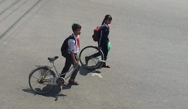 Hài hước hình ảnh học sinh dắt xe đạp đi ngoài trời nắng: Đứa cầm bánh trước, đứa dắt thân sau